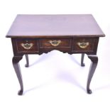 An 18th century oak lowboy the rectangular top with moulded rim, over three small drawers with brass