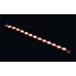 A 14ct yellow gold and coral bracelet comprising of thirteen oval cabochon coral segments, 17 cm,