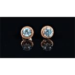 A pair of 9ct yellow gold and blue topaz ear studs each claw-set with a round cut topaz within a