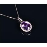 An 18ct white gold, diamond, and amethyst halo pendant set with a faceted oval cut amethyst