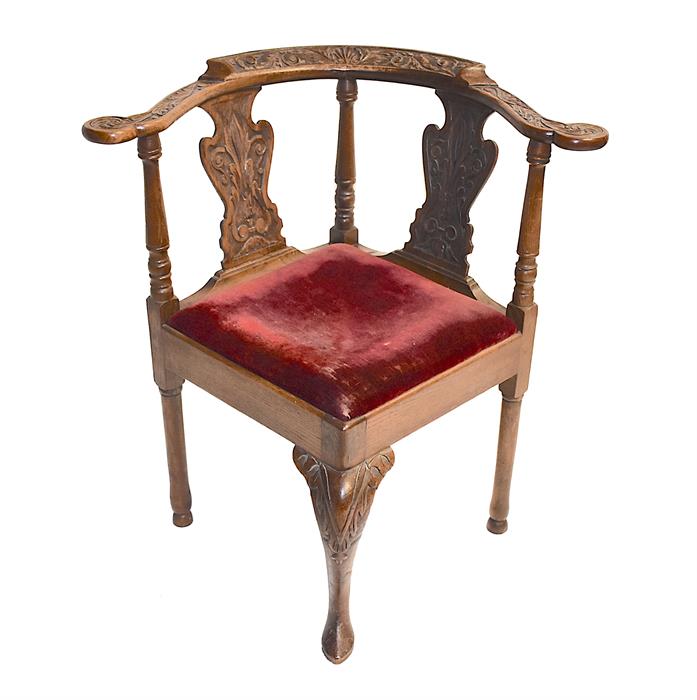 A Victorian carved oak corner chair the frame carved with scrolling acanthus and scalloped