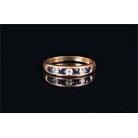 An 18ct yellow gold, diamond, and sapphire ring channel set with three round brilliant cut