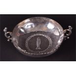 A late 19th century Eastern white metal bowl the centre embossed with a fish and laurel wreath,