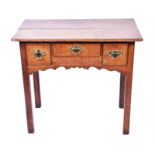 An 18th century oak lowboy the plain top with moulded rim, over three small drawers with brass