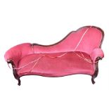 A Victorian carved mahogany chaise longue with ornately carved show wood frame and crushed raspberry