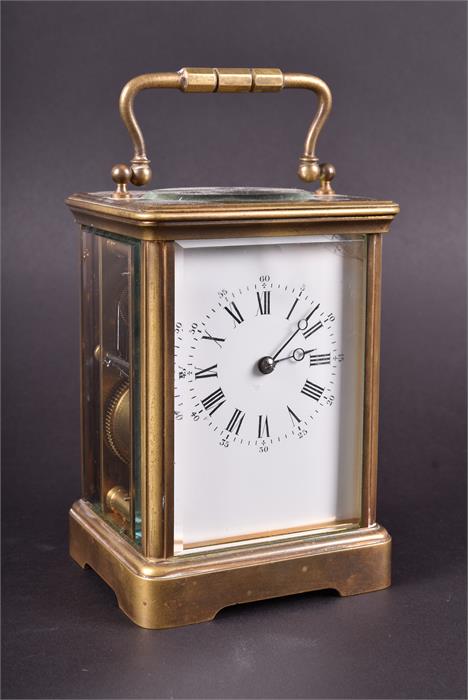 A Victorian brass carriage clock the white enamel dial with black Roman numerals, striking on a
