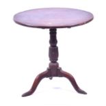 A Georgian oak tilt top table the triple plank top, mounted on an associated turned column to tripod