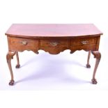 A Queen Anne style walnut bow-fronted serving table the cross-banded top over three small drawers
