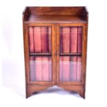 A small 1930s oak bookcase with a pair of glazed doors, enclosing a set of Encyclopaedia