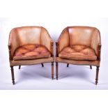 A pair of leather tub chairs upholstered in rich tan leather with button seats, and supported on