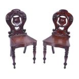 A pair of early 20th century dark wood shield back hall chairs with carved cartouche, turned back