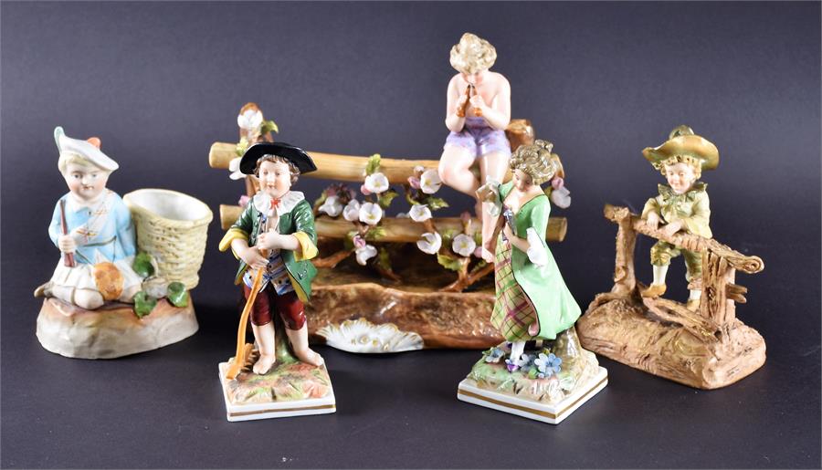 A group of five porcelain figures to include a model of a boy leaning over a wooden fence, marked