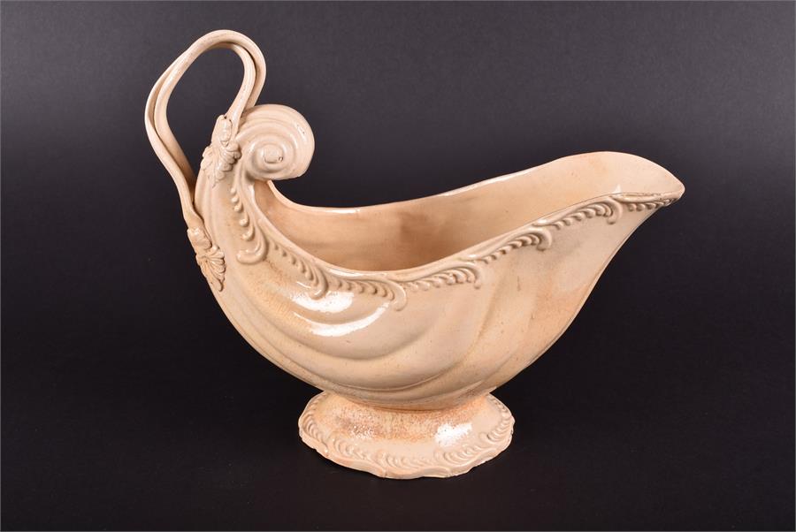 An 18th century creamware shell shaped sauce boat the rim with moulded scrolled decoration, with