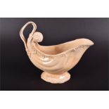 An 18th century creamware shell shaped sauce boat the rim with moulded scrolled decoration, with