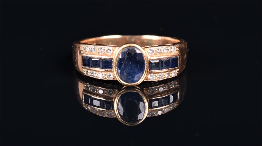 An 18ct yellow gold, sapphire, and diamond ring centred with an oval mixed-cut sapphire, flanked