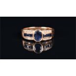 An 18ct yellow gold, sapphire, and diamond ring centred with an oval mixed-cut sapphire, flanked