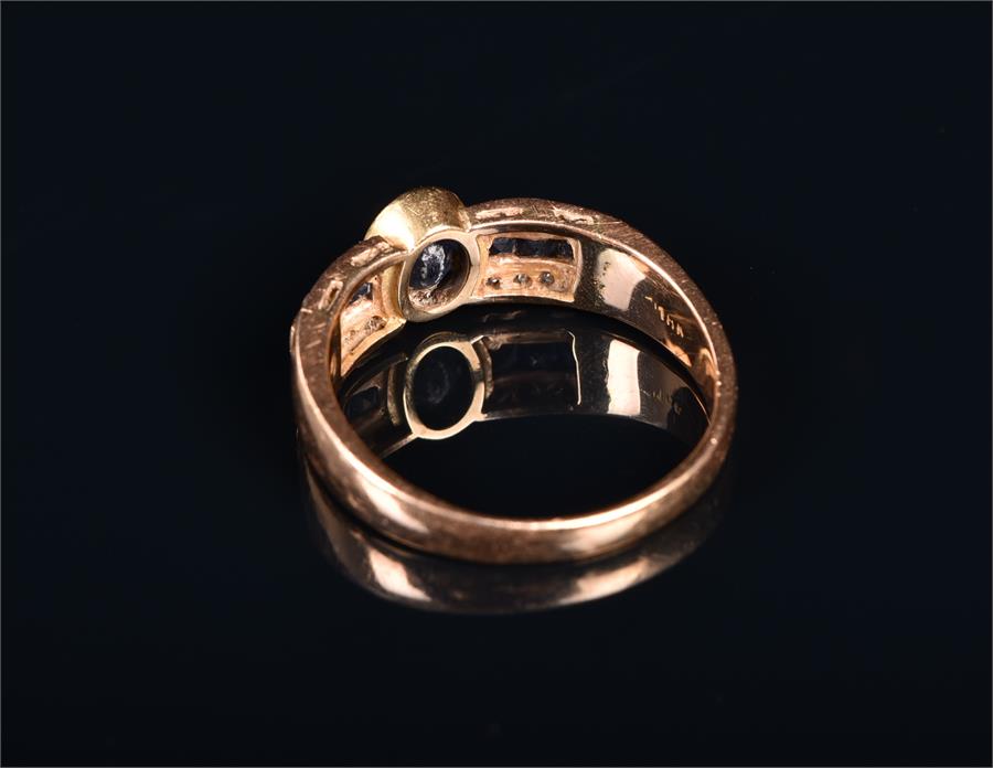 An 18ct yellow gold, sapphire, and diamond ring centred with an oval mixed-cut sapphire, flanked - Image 2 of 2