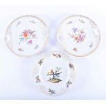 A pair of Dresden painted porcelain plates decorated with sprays of flowers, with looped handles,