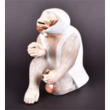 An early 20th century Japanese porcelain figure of a monkey in seated pose, wearing a robe and