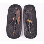 A pair of 1950s cast plaster wall plaques finished in matte black and gold paint, depicting a