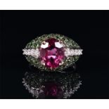 An 18ct white gold, diamond, rhodalite garnet and demantoid garnet ring centred with an oval-cut