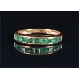 A 9ct yellow gold and emerald ring the half eternity band channel set with alternating round and