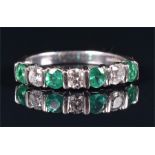 A platinum, diamond, and emerald ring bar-set with four round cut emeralds and three round