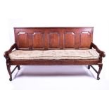 An 18th century oak long settle / bench seat with panelled backs and open arms, drop-in padded seat,