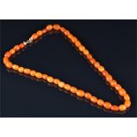 An amber beaded necklace comprising of oval beads, with yellow metal clasp, 39 cm long, 9.5 grams.