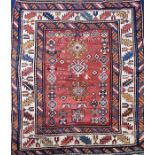 An old Eastern woven wool rug evenly worn with a terracotta ground with geometric motifs and running