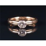 A 9ct yellow gold and solitaire diamond ring rubover set with a round brilliant-cut diamond of