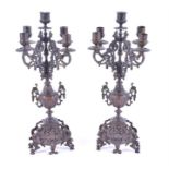 A pair of Victorian bronze five light candelabra with ornately scrolling branches and embossed