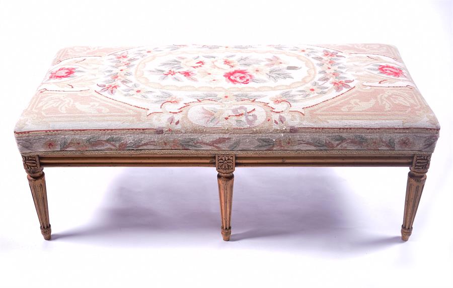 A gilt painted upholstered stool with needlework upholstery, the frame, supported on six fluted