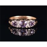 A 9ct yellow gold, diamond, and amethyst ring set with three round cut amethysts, interspersed