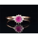 A 9ct yellow gold, diamond, and ruby cluster ring set with a round-cut ruby surrounded by round