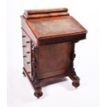 A Victorian figured walnut Davenport the top with stationery compartment, and rising writing surface