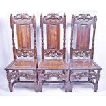 Three 18th century oak single chairs with carved foliate crests, panelled backs with column sides,