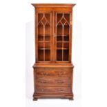 A modern yew wood veneered dwarf bookcase with a pair of astragal glazed doors enclosing shelves,