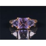 A 9ct yellow gold and iolite ring set with a square cut stone flanked by two trillion cut stones, of