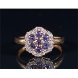 A 9ct yellow gold, diamond, and tanzanite floral cluster ring set with round cut tanzanites within a