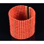 An 18ct yellow gold and coral beaded cuff bangle comprising of 13 rows of rounded coral beads,