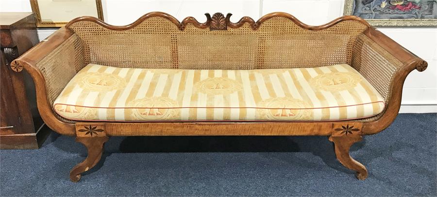 A Regency style bergere scroll end sofa with cane work back and arms, well carved frame with