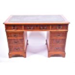 A reproduction yew wood pedestal desk the green inset leather top over three frieze drawers with