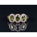 A 9ct yellow gold, diamond, and chrome diopside ring set with a triple cluster of three oval-cut