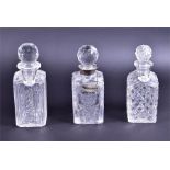 Three late 19th century cut glass decanters two with enamelled decanter labels for port and gin, and