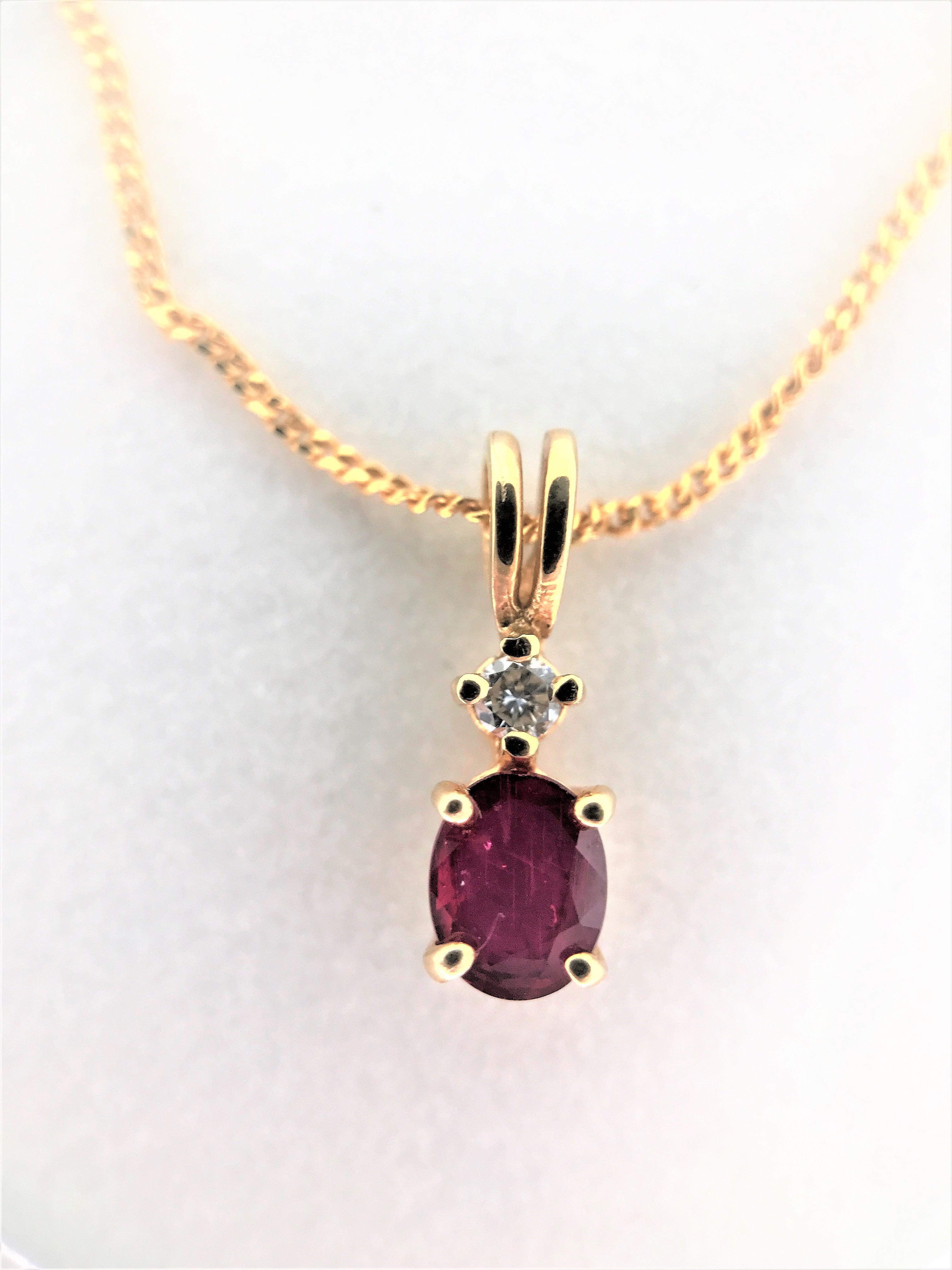 Oval shaped garnet pendant with 1 diamond on 16'' gold chain. 14k yellow gold. Tital diamond