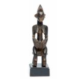 Senufo, zittend vrouwfiguur op zetel, met lichaamstatoeages en zwart patina. h. 20 cm.