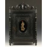Zwart gelakt houten eendeurs kastje, ca. 1900 glazen ovaal waarin plaatje. h. 58 cm.