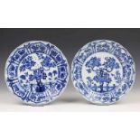 China, paar blauw-wit porseleinen borden, Kangxi, met decor van bloesemboom bij hekwerk, de rand met