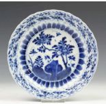 China, blauw-wit porseleinen schoteltje, Kangxi, met decor van bloesem (flintertje) diam. 16 cm. [1]